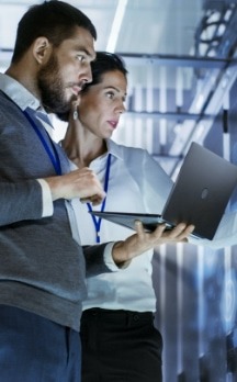 Man and woman standing in a data centre looking at a laptop